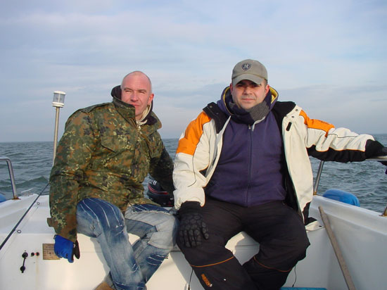 Thomas am Steuer mit Tuncay im Heck des Bootes, an einem leicht bewölktem Morgen