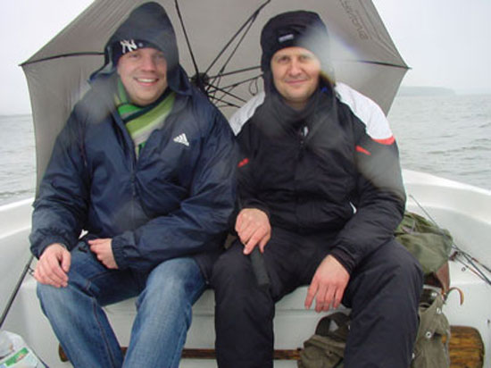 Dima und Jan bei starken Regen unterm Regenschirm sitzend im Boot